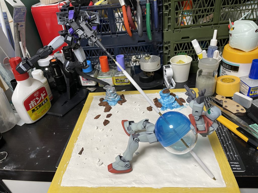 ビームは真鍮線とプラパイプの組み合わせで作ってます。画像の段差になってるとこはパテで整えてます。パイプは外周に5ミリと3ミリを使用。真鍮線ライフルから出てるとこに1.5ミリ、固定軸として3ミリを使用。1.5ミリのほうは3ミリパイプの中心に来るように接着。ジムは上下が爆発により泣き別れしてる感じにするために真ん中にガチャガチャのカプセルを入れてます。カプセルにそれぞれ刺さってる感じ。造形物はバークチップとスタイロフォームで。スタイロフォームを適当なサイズに切ってボンドで接着。乾燥が待てない程気が短いので推奨できない方法で造形。安全ではないので教えません。初めて作りましたがもうちょい大きく作った方がスケール感的によかったかも。