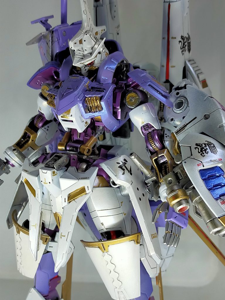エアブラシで塗装したのはホワイトやパープル、シルバーがメインでゴールドはエナメル、装甲裏などもエナメルのシルバーで部分的に筆塗り。機体全体に3色のパール塗料を吹き、ガイアノーツの箔デカールなどを貼りクリアで光沢仕上げにしてあります。