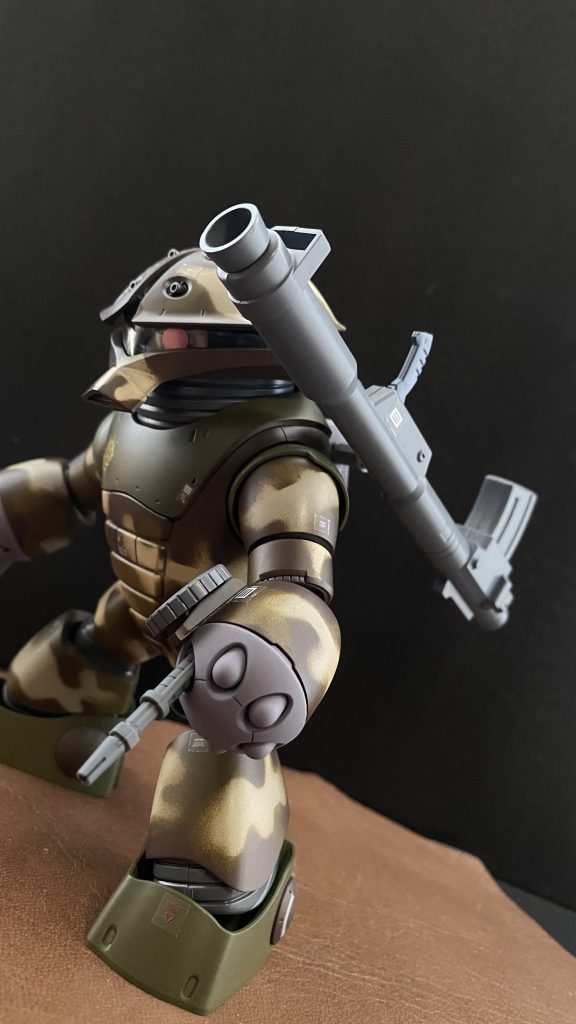 本機の左腕には、より汎用性を高める為、ザクマシンガンが内蔵される。この機体の構造上、自身によるマガジンチェンジは不可能である。背部に装備されたバズーカは、僚機の武装として担架されるが、背中に担架された状態でリモートにより、トリガーにアクセスし発射することも可能。