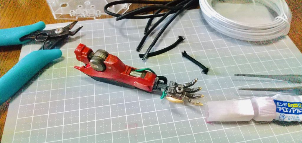 ルプスレクスの右腕は、試作EMP発射機構が備わっているという設定なので、針金や靴紐を使って、コードが、ぐちゃぐちゃと露出している様子を表現しました。また発射のためのポーズをとれるよう、手首の接続ジョイントを変更して、上下に手が稼働するようにしています。