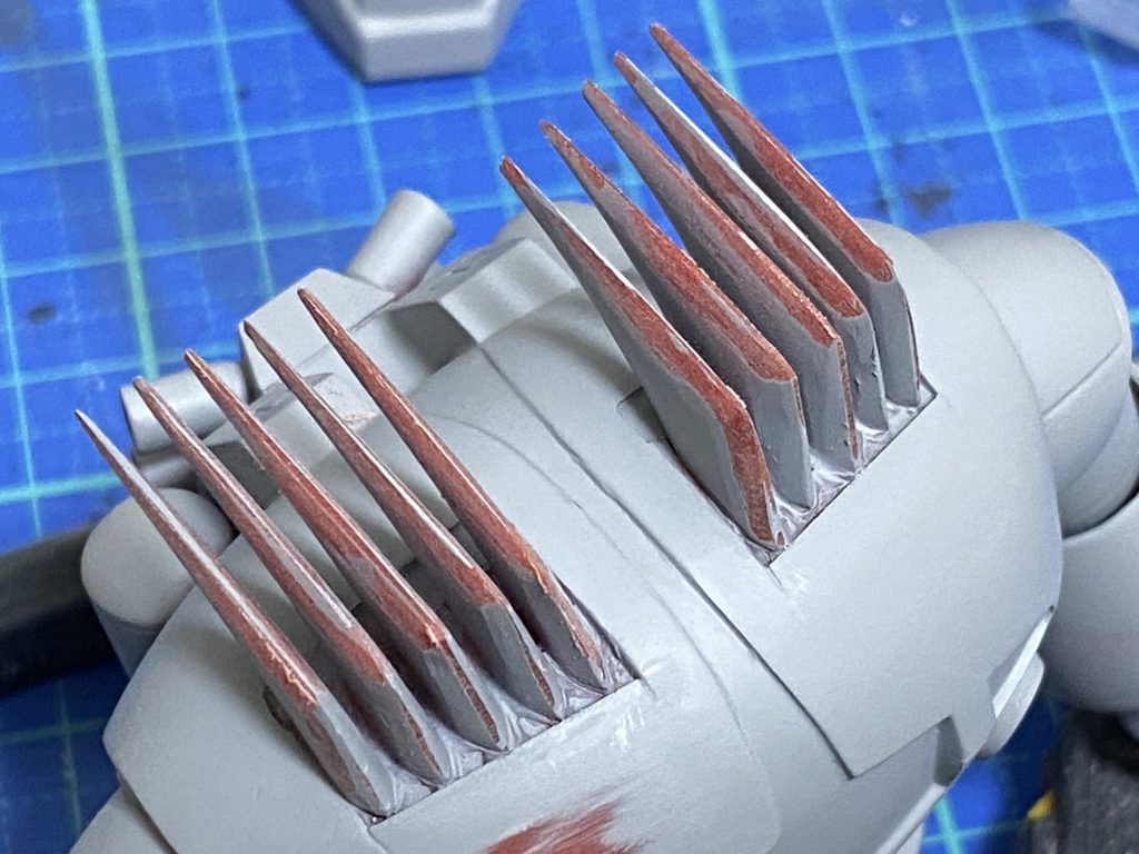 ①ブーメランカッター調整造形が厚ぼったい上に、1枚ごとに形状が微妙に異なる(!)ブーメランカッターは、頭部に仮接着してからリューターやナイフを使い、現場合わせで形状を整えました。その後一度剥がして、1枚ずつフチを削ってエッジを出してから再接着しています。取り付け位置を調整して、外側から内側にかけて1枚ずつ少し前に出しています。こうすることで頭部のカーブと調和した自然な並び方に見えます。