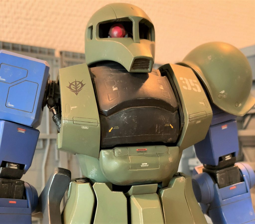 胸部はどうしようか悩みましたが、コックピットパネルの中央の土手を削り取るのみにしました。設定画の旧ザクのような形状に改造する自信と気力が無かったのと、ザクⅡへの進化をイメージして最低限の加工で済ませました。旧ザクでこの部分の強度不足が指摘された為、ザクⅡで中央部を増肉した、という脳内補完です。腹部もあまりいじらずシンプルを心がけ、MGの造形を手本にしながらパテを盛って成形しました。このお腹から胸辺りの造形が旧ザク化の悩ましい部分だと思います。完全に満足はしていませんが、まあ何とか不自然というレベルでは無いくらいには調和しているかなと自分を納得させ、早々に切り上げ泥沼に嵌るのを避けました。