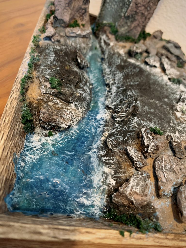 流水はエメラルドグリーンのレジンをベースに所々ブルーを重ねて流し、水辺の深い・浅いの濃淡が出るように工夫しました。さらに上から木工用ボンドを塗り延ばし凹凸を出し、白のペイントマーカーでドライブラシをして水面が泡立ってる様子など立体感を出しました。