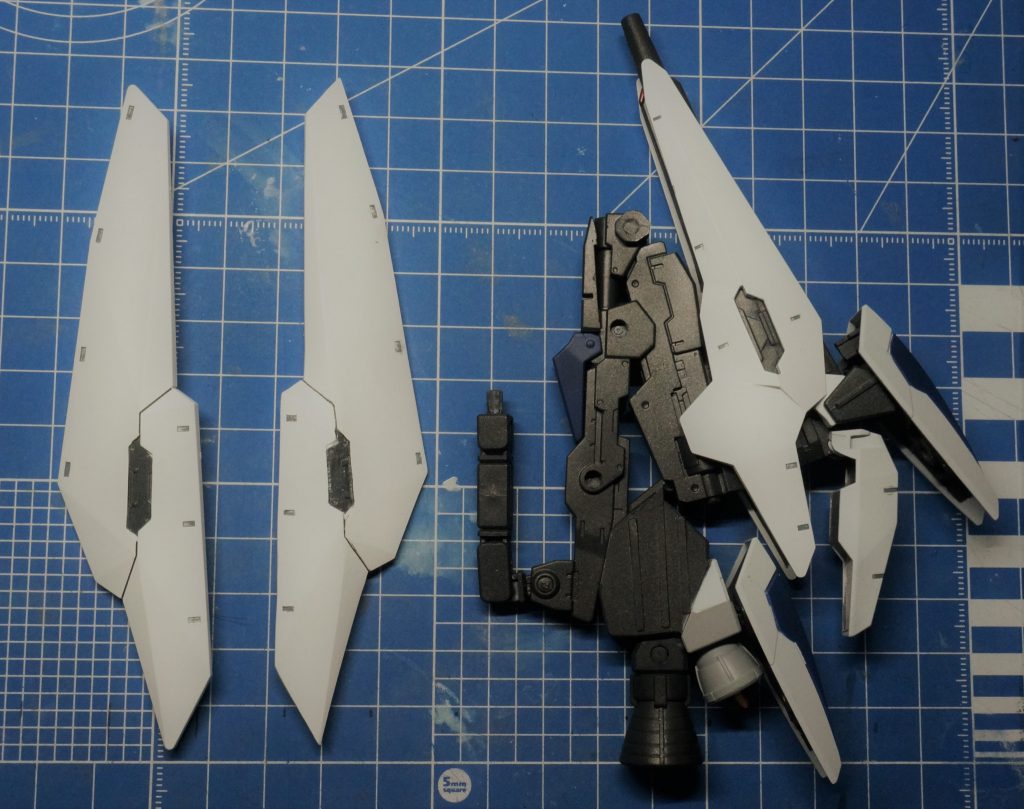 ヒュージシールドバインダーテルティウムアームズのヒュージブースターとロングビームライフルを一体化。みんなが一度は考えるであろうシールドバインダーの対象部品をプラ板積層からの削り出しで作製。左が元部品、右が作製した部品。アーム部は砲撃姿勢実現のためには可動域が足りなかったのでジムカーディガンのアームを使用。