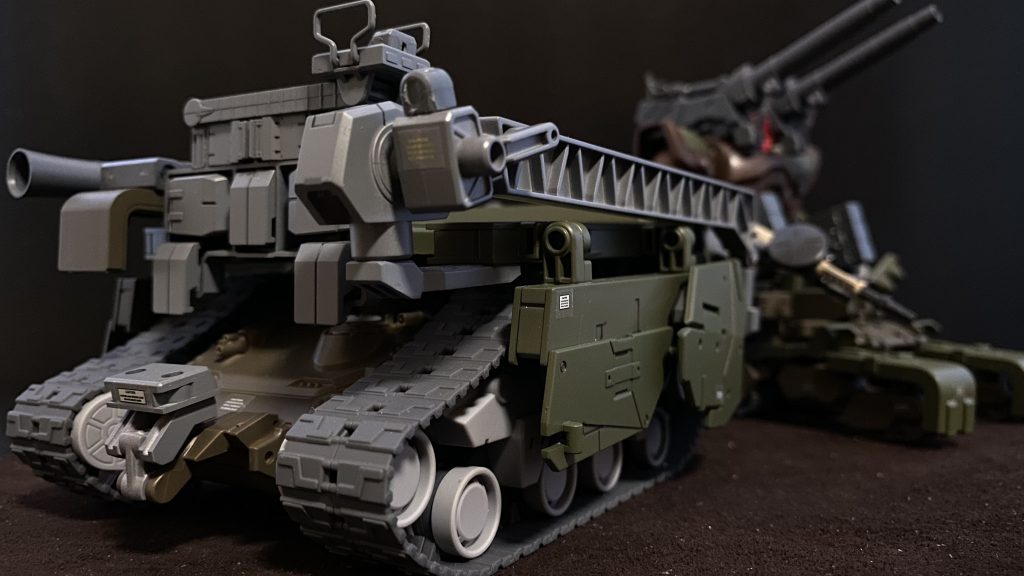 後部ユニット HLV打ち上げ基地において、HLV内に物資を搬入する際に使用されていた、運搬キャリアユニットを、腕に覚えのある工兵隊の整備兵らが魔改…、いや、改修し、彼らの「家」として生まれ変わった。元は、一年戦争より10年以上前に、地球連邦軍で採用されたRTX-65ガンタンク初期型の下半身部分(と、言ってものだろうか)を転用したキャリアユニットである。 優秀?な彼ら整備兵による