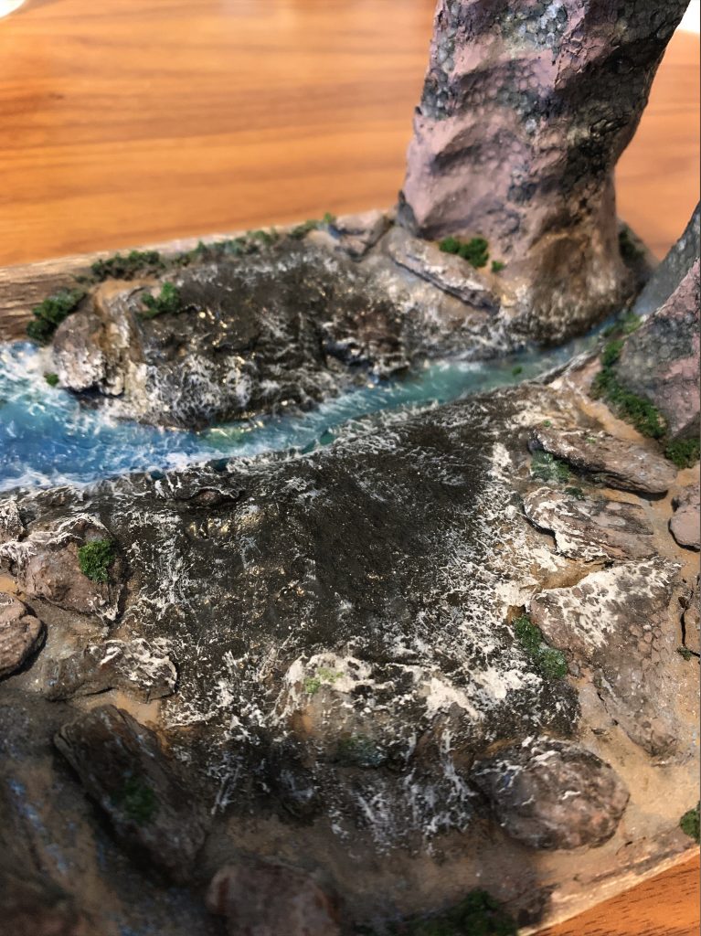 写真では分かりづらいですが、流水が飛び散り地面が濡れて見えるように工夫しています。あらかじめズゴックの配置位置を想定した場所に液体のりを塗りたくり光沢感を出しました。その上から白のペイントマーカーでドライブラシをかけて飛沫を表現しています。