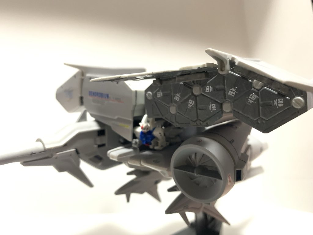 作品中ではとくに模様的なもののない機体ですが、設定上は試作機でありデータ運用の為の機体の意味合いが強いと思いわれるので、機体各所にいろんなデカールを貼りつけて「THE　試作機」という感じにしてみました。コンテナを中心にデカールを貼りつけまくって派手めにしてみました。コンテナ内が寂しいので左右８こずつのハッチの蓋に１～８のナンバーも貼りつけました。