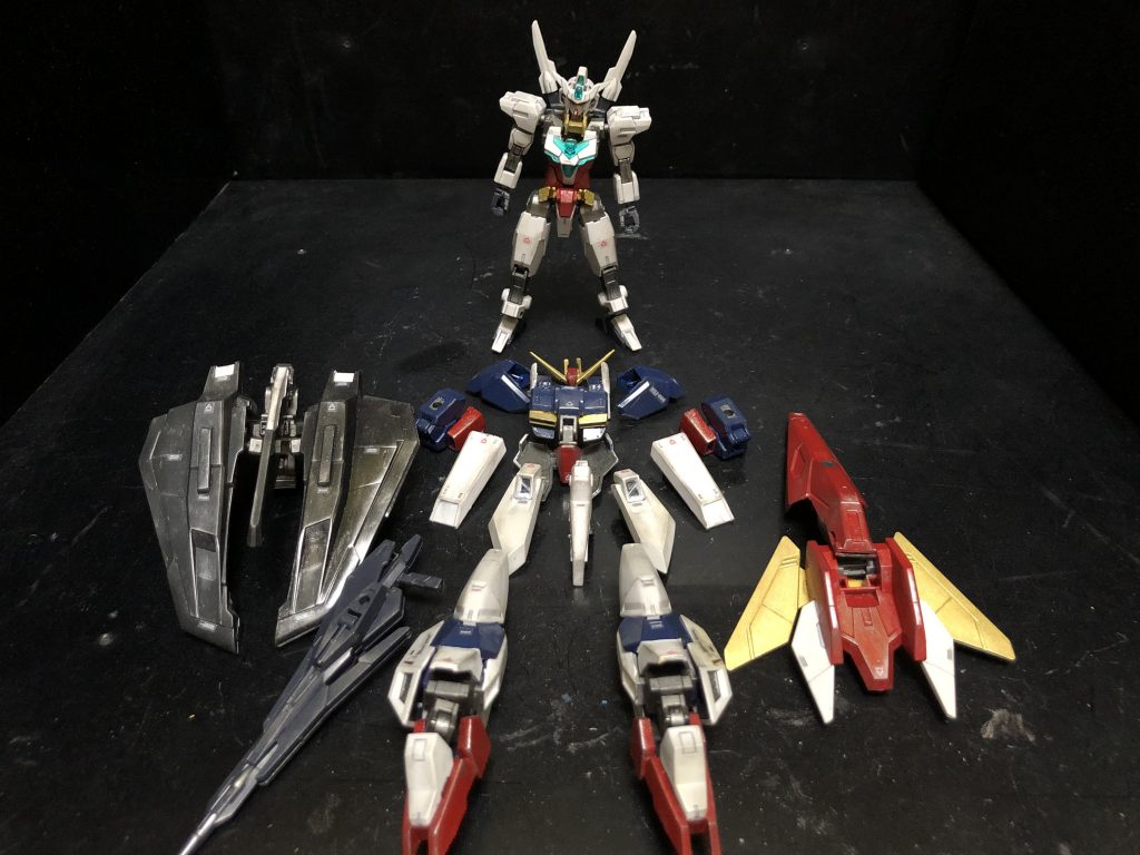 oyz「新規で何にも購入しなかったんですよ〜。全部ジャンクで事足りました。」カザミ「よくパーツあったな。」oyz「そんな感じで、全体的にゼータっぽい感じに出来たんです〜。」カザミ「それでフェイクゼータって訳かよ。」oyz「それじゃあココでお待ちかねっ！フェイクWRへの可変といきましょう！」カザミ「なに！？コレWRになるんかよ！？」oyz「それは当然でしょう！アーマーだけでの可変ですけどね。ジョイントパーツ無しで、WRになりますよ〜！」カザミ「うおお、それはイイじゃねえか！」oyz「それでは可変シークエンスですっ！」① パーツを全てキャストオフ！② バックパックユニットを定位置に可変させる。③ シールドを取り付け。④ アンテナパーツ、腰パーツ一式をまとめて、機尾に取り付け。⑤ 肩パーツ、腕パーツを取り付け。⑥ 脚パーツを変形して取り付け。⑦ サイドアーマーを胸パーツに接続。胸パーツを変形して取り付け。⑧ ライフルを縮小して取り付けたら。⑨ あっという間にフェイクWRの完成っ！