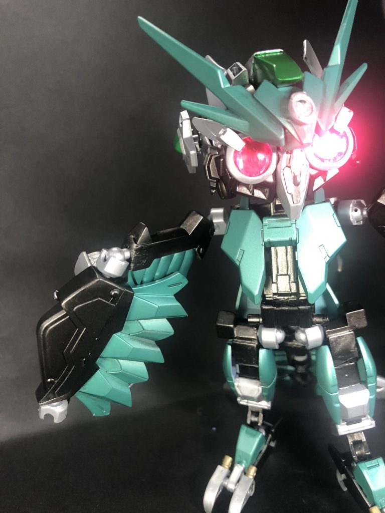 チャームポイントの大きな目から特殊な光を発する事が出来るホー!敵機の動きを止めたり、機体のコントロールを奪ったりとだんだん効果が強くなるホ〜。ホウ…でもコレ使うとエネルギー結構使っちゃうから疲れるんだよね…ホゥどほどに使うのがコツね。解説①心担当その1、瞳術ハットリの頭部(主に瞳部分)には、暗視や解析など様々な視覚的機能が集約されている。その中には敵機をハッキングする機能があり、光の照射時間の長さで段階的に効果が現れる。照射〜1秒で敵機の動きを止め、3秒以上の照射でハッキングが完了し、コントロールをハットリが奪取する。(その際ハットリ本体は簡易AIが操作する)制作メモ①瞳部分にはHGエクシア(多分アメイジングエクシア)の膝部分を使用。クリアパーツは、通常時はアメイジングの緑、術発動時はダークマターのピンクで付け替えてあります。ちなみに写真は無加工です。目が光ったように映ったのは偶然の産物ですw