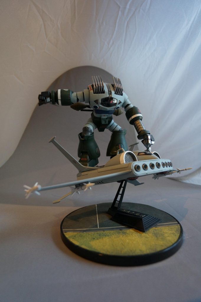 ↑小指でフックを摘まんでます(笑さて、ここでゾゴックに関する考察です。ゾゴックの腕の伸縮機能は一般的に拳を打ち出す「アームパンチ」であると解釈されています。私はこの設定に疑問を持っています。拳で殴るのであれば、拳には体重を載せて打撃力を上げるべきです。拳を射出し力学的な絶縁状態にしてしまうと打ち出された拳には、拳そのものの重量しか付加されておらす、軽いパンチになってしまいます。運動エネルギー上は、軽いものでも弾丸のような高速で打ち出せば打撃力を上げられますが、腕の伸縮機能に、そこまでのスピードが出せるようには思えません。私の仮説は、伸縮アームは拳を射出するものではなく、アッガイと同じく腕のリーチを伸ばし、遠くにあるものを掴むためではないかと思っています。腕を伸ばすことにより、ロッククライミングをしたり、この作例のように腕を係留フックのように用い、より自由な姿勢で、ドダイの上で大立ち回りが出来るようになると思います。いかがでしょう?