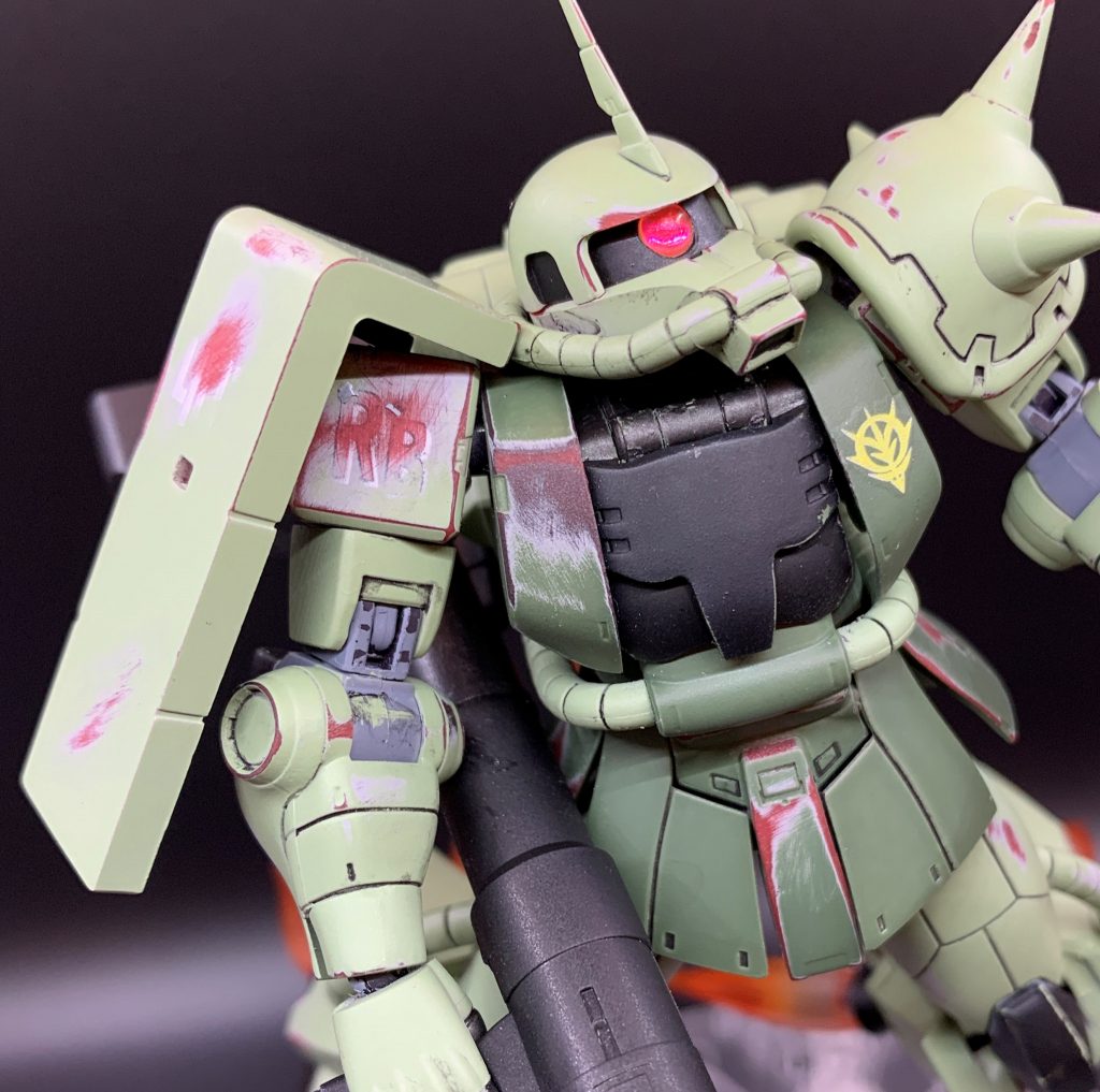 肩部は擦れてうっすら「RB」の文字が露出しています。この辺りは構想通りに上手くいって満足した点です。フィギュアがアニメっぽい造形なので、バランスを考えてコーションデカールの類は貼らず、ジオン軍章のみにしました。塗装は下地にグレーサフを塗りましたが、これは失敗でした。赤と緑の間にグレーが見えるのは想定外にみすぼらしいというか、印象がぼけてしまいました。そのまま赤の上に緑を塗るか、サフを塗るにしてもブラックにしておけばよかったです。