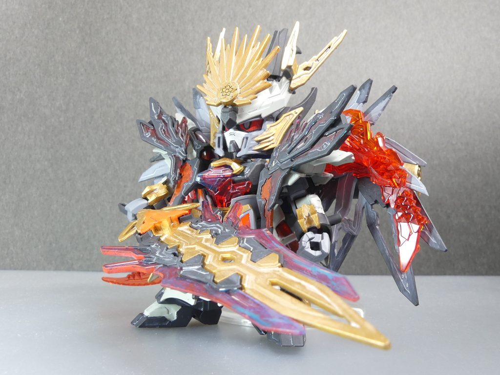 魔王信長ガンダムルシフェル:曹操を倒した信長エピオンのif設定として製作されたガンプラ。同時に、キヨス・オニコロシの覇道を導く存在。特に関節部が「エルドラパーツ」で強化されており、近接・射撃の双方において通常サイズのガンプラと張り合う事ができる。メモリと仮面の同時使用:メモリは「エルドラパーツ」から切り出したエルドラスネークメモリ。仮面は信長エピオンの独自ギミック。身に付けたものの能力を強化する。GBNの本連載設定では、本来はどちらか一方のみ使用可能。翼にはへし切り長谷部やエフェクトパーツをマウント可能。魔王銃装備だとさすがに素立ちはできません。