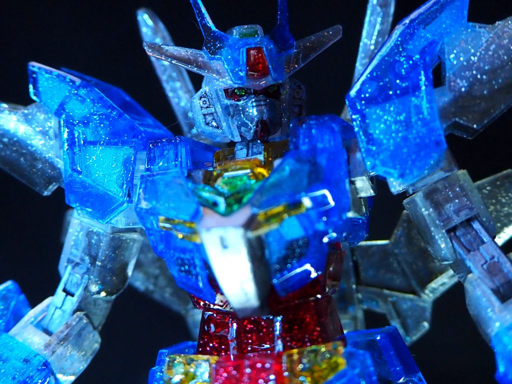 頭部パーツはモノアイ・顎部分が一体化されていてそれがレッドのクリア素材だったのでシルバーで塗って赤の色合いを消しています。コアガンダム部分の胴体（胸）もグレーパーツだったのでシルバーで塗っていますがその分、下からの光が通過せずに頭部・顔が暗くなってしまったので正面側にライト付きの鏡を撮影時に急遽加えました。あ、今思えばモノアイ部分と顎部分でパーツを分割して接着した方がクリアの綺麗な光源通過が出来たかも…次の課題とします。