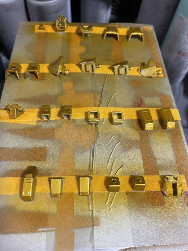 クリアイエロー+クリアオレンジ+クリアの混色を溶剤と1:1で混合しブラシ塗装。原色のクリアカラーに透明クリアを混ぜることで塗料の濃度を落とさずに色目を薄くすることができます。確かに塗装しやすいと思いましたが、反面、薄い色を重ねていくのでパーツごとの色の差が出ないように均一化させるのが難しいです。塗装での金色表現は永遠の課題ですね。下地をシルバーとゴールドを使いましたが、ゴールドの部分は一段イエローが濃くなるのでRGのような雰囲気にできないか、というテストでした。クリア塗装に関しては、くわしくは模型サイトNIPPERの該当記事を参照してください。