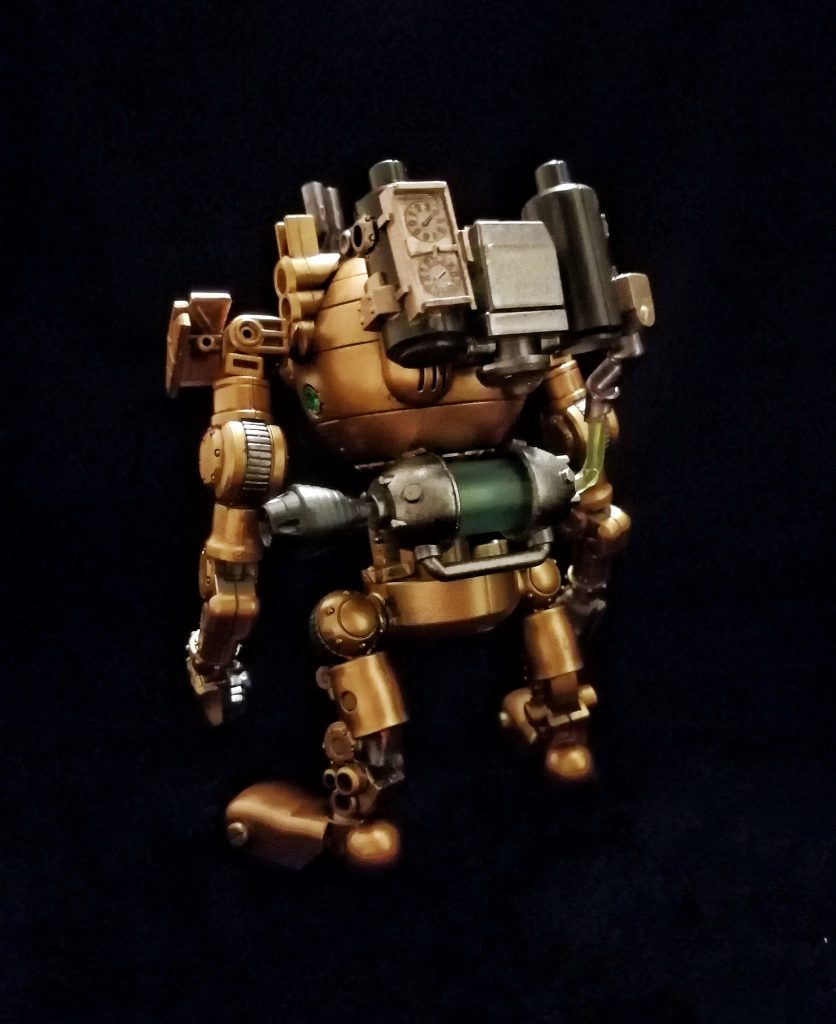 STM-008 マンマルは、スチームパンクをテーマに、「HGUC ボール」と「HGBD モビルハロ」をベースに、ジャンクパーツとミキシングして作られたガンプラです。正面には大きく前に突き出たカメラアイがあり、本体上部に排煙・放熱のための排気パイプが伸びています。背部に本機の動力となるスチームエンジンを搭載しています。