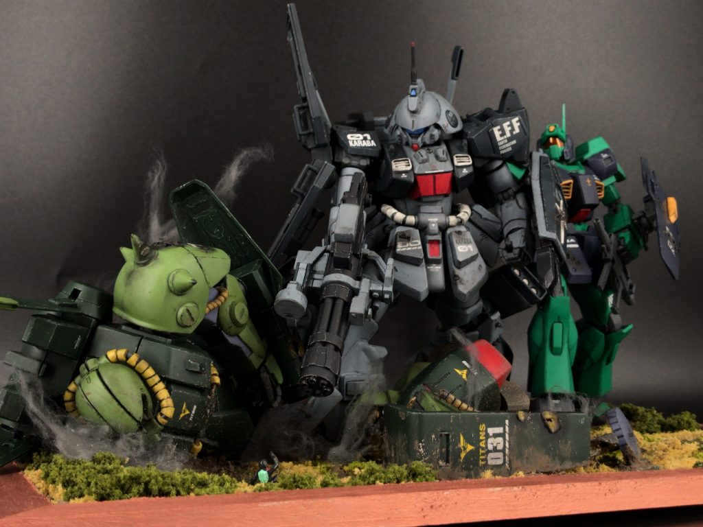 ちょっと引いたアングルから一応、やられてるのがティターンズなんだよっていうのをぱっと見で強調するためにわざとティターンズのエンブレムがいっぱい見えるようにエンブレムを貼ったシールドや胴体、足のスラスターが正面に向くように配置しました。ドミンゴやネモにデカデカとEFFのデカールを貼ってるのも、エゥーゴやカラバが自然と連邦に吸収され始めて、もうティターンズが反連邦扱いされてる時代設定なんだよっていうのを作品を見た方達に感じてもらえるように配置しています。