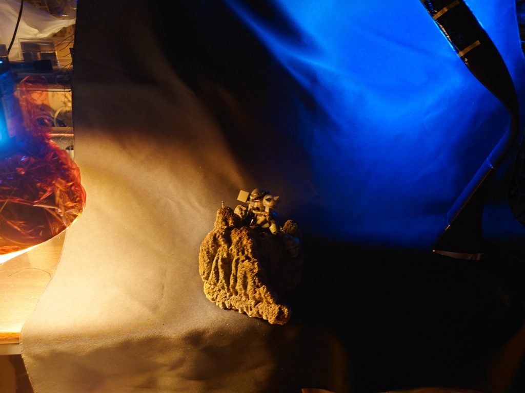 撮影風景です。今回は、園芸用の軽石を岩山に見立ててのジオラマです。朝焼けの表現にピンクとイエローのフィルムを使い、反対の夜空にブルーのフィルムを使いました。光源はその二つで、部屋照明は無しです。身近な物で手軽にできるを、コンセプトにやってます。このジオラマだと照明色を変えれば、火星風景にも応用できるかな? いずれまた使いましょう。