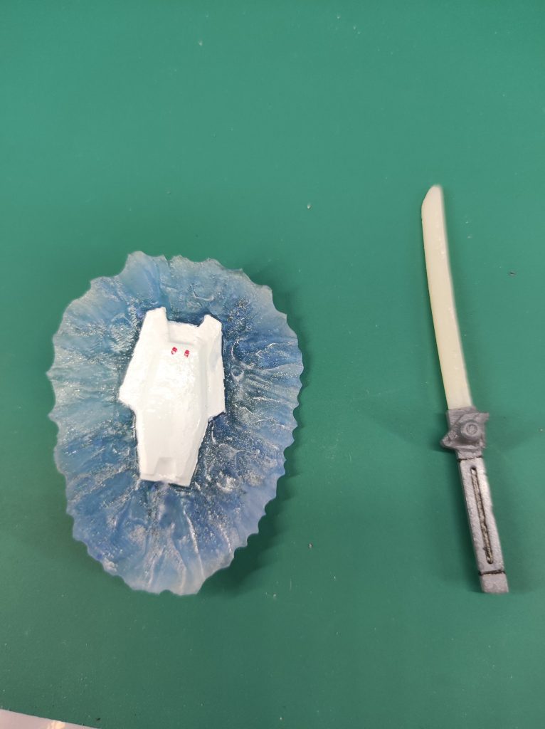 ビームシールド基部の塗装に失敗しました。が、ビームシールド部はまぁまぁの出来でしょう。次は失敗しない！刀の方は設定としては火星のマウンテンサイクルで見つかった、ここにあるはずのない物。ビームでもMSのパワーでも傷一つつけることができず、まったく欠けもしない、そして異様なまでに軽いこの小刀サイズで生身の成人男性が余裕で持ててしまうほど発見した彼らには知る由もないが、これはとある人類播種を目的とした船で作られた物と同一の素材、超構造体製。ただ、生物の切断には使えるしまったく刃こぼれもしないが、重量で叩き切ることが出来ないため鉄血の世界では無用の長物。コンポジットレジンならセラミック入ってるのでプラとは桁違いの強度だし、新素材超構造体のイメージにあうかなーと。T風さんも「陶磁器みたい」て言ってたし。