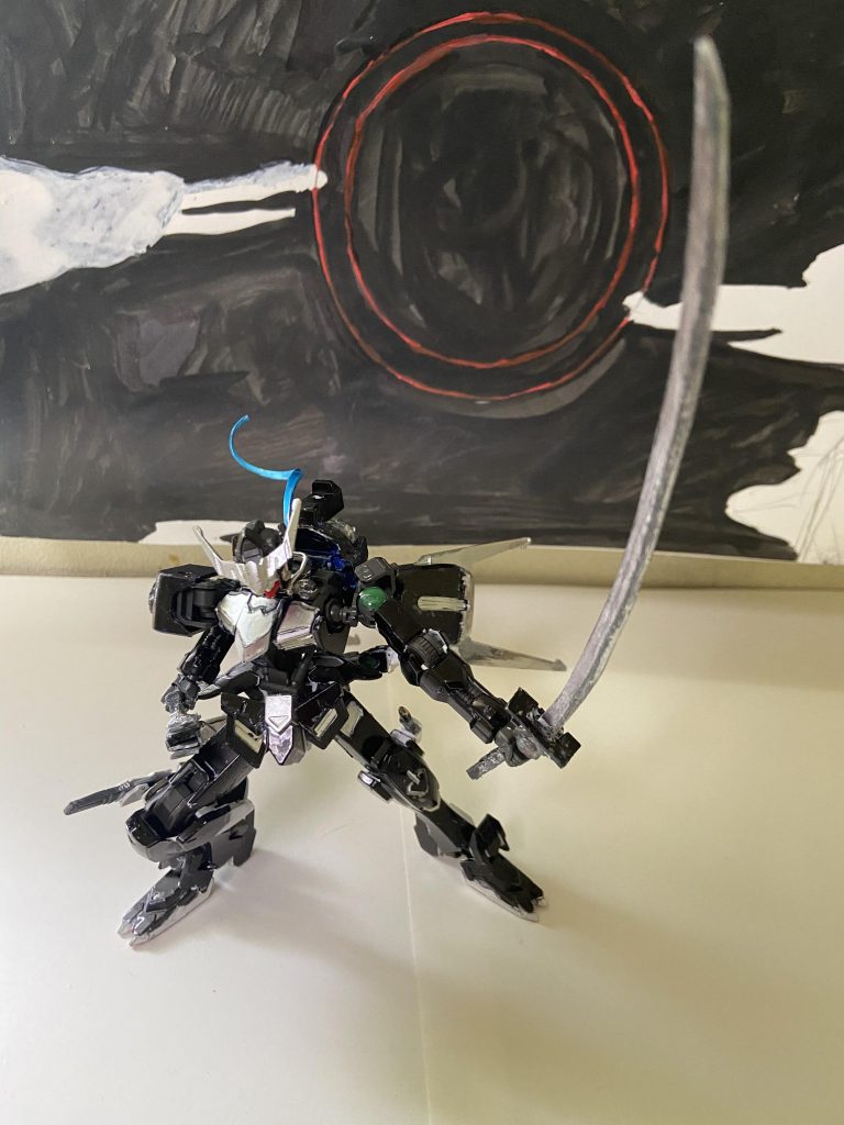 武装解説長刀三日月 バルバトスの身の丈以上の長さを誇る刀フリートの太刀同様鍔の部分にコンデンサーを取り付けられており、太刀と違い粒子の斬撃を飛ばすことはせず切れ味の強化に使われている、鞘と刀がセットで1つの武装となり和道は三日月を利用した抜刀術を基本戦術としている。