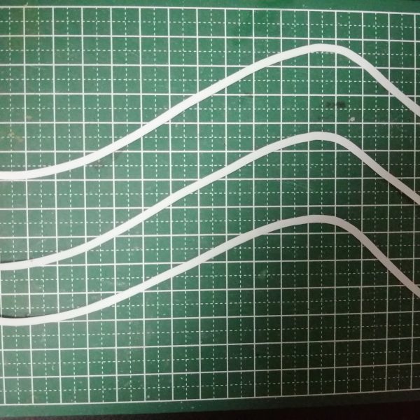 ハンブラビの羽根の上辺に貼るプラ板を切り出して、仮止めしてみました。 エポパテで作るか、プラ板で作るか悩んだのですが、エポパテは後で歪みを修整するのが面倒に思えたのでプラ板工作を選択。とはいえ、どうやって切り出したものか？とりあえず、プラ板にマジックで線を引いて、デザインナイフを使いフリーハンドでエイヤッとやったものの、まぁ平行にはなりません。 そこで、マスキングテープを平行にカットする工具があるのを思い出しました。某マンガの連刃刀みたいに、ナイフの刃が平行に2枚セットされてるヤツです。買おうか悩んだけど、値段が折り合わずに買わなかったんだよな。今すぐ欲しいのだが、時刻は深夜1時を過ぎているので、買いに行くこともできない。要はデザインナイフの刃が平行に並んでいれば良いわけで、なら作ってしまえ！製品ではなく、今回使えればよいので、刃の交換機能や刃間の隙間を変える機能は不要と割り切ります。ダイソーのデザインナイフの刃の間にスペーサーとして1ミリプラ板を2枚挟んで瞬着で固定。そのままだと使いにくいので、ちょうど寿命を迎えたマッキーをバラして、合体！おおっ、サイズピッタリ！ 早速使ったものの、欠陥を発見。カーブを切ると、刃がたわんで平行を維持できなくなります。その対処として刃先近くまでプラ板のスペーサーを入れました。これで冒頭のように、羽根の上辺に貼るプラ板を切り出せました。 （2枚目）