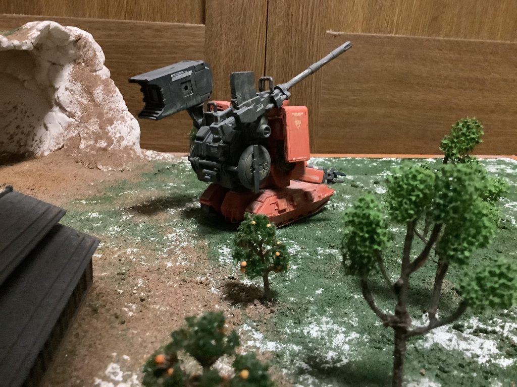 後ろからの一枚。サンダーボルト版ザクのバックパックを上下逆さまにして取り付け、EZ-sRの滑空砲とコトブキヤのミサイルランチャーを装備しています。左右に1機ずつレドームを取り付けて命中精度や地形把握に用いる設定です。そのせいか、バックパックが重すぎて後ろに倒れるので、マゼラ・ベース内に金属製のウエイトを入れて転けないようにしています(笑)