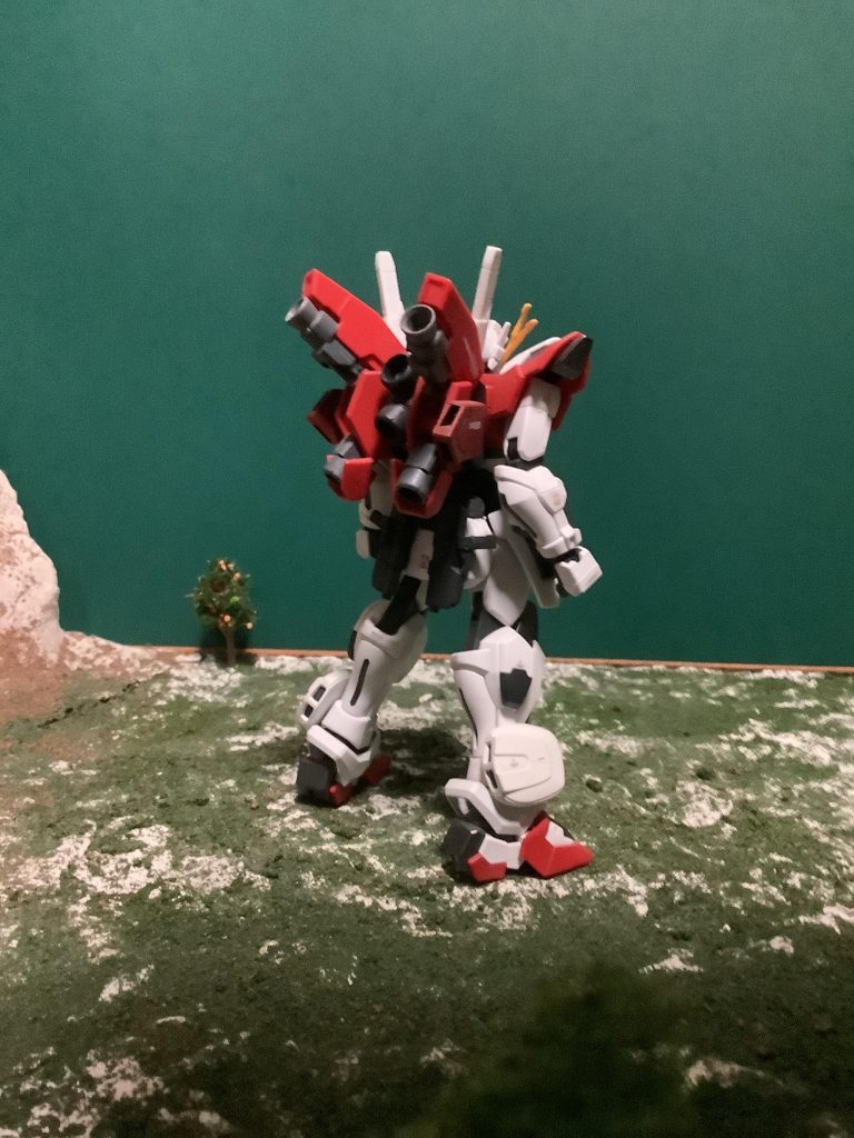 後ろからの一枚。バックパックをディナイアルガンダムのものをベースに、リボーンズガンダムのバックパックを合体させ、ノズルを増やして機動力を上げています。敵機に背後を取られる事も想定して、ミサイルやダミー、フレアを放出できるポッドを搭載して、相手の意表を突くことも可能です。また、リアスカートにストライクノワールのショートビームライフルをハンドガンとして装備し、ある程度の遠距離攻撃が可能です。そのままでは付かなかったので、ストライクノワールのサイドスカートごと移植し、パテで整形しています。