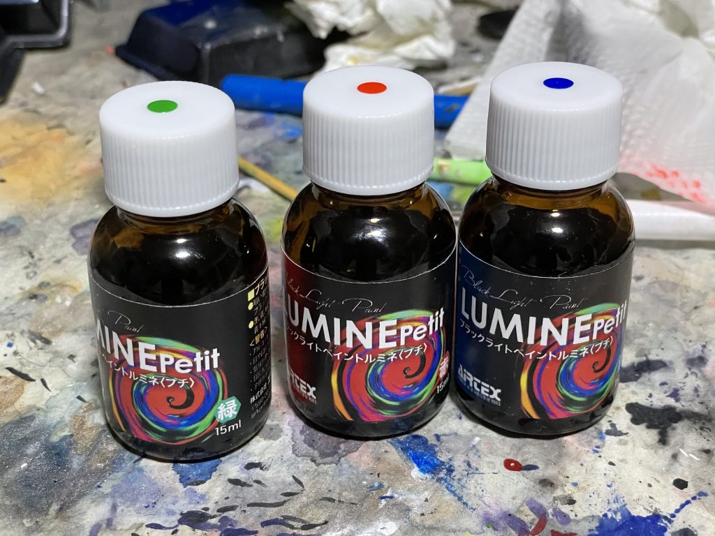 塗装レシピ断りのないものは水性ホビーカラーです。蛍光色は可視光では不可視になるエアテックスのブラックライトペイント ルミネ(写真)を使用しています。サイコフレーム: 黒→シルバー→メタリックレッド(ラップ塗装)→ゴールド(ラップ塗装)→クリアレッド→ルミネ赤ボディグレー: フィールドグレーボディ白: フィールドグレー→ガンダムホワイト→白(ハイライト)青: 調色したダークブルー→クリア+CCパールブルーゴールド: 黒→シルバー→クリアイエロー+クリアオレンジアイパーツ: 黒→シルバー→クリアグリーン→ルミネ緑ハロ: アクリジョンデイトナグリーン+イエロースミ入れ: Mr. ウェザリングカラー マルチブラック、およびコピックモデラー0.02 Blackブラックライトペイント ルミネはアルコール系塗料でしゃばしゃばなので薄めずそのままエアブラシで吹けます。普通に吹くと全然見えないので、保護メガネにブラックライトを輪ゴムで固定した状態で吹いてます。はっきり発光させるには数回重ねて拭いた方が良さそうです。アニメの超絶龍破斬の演出イメージで全身にルミネの赤をかけてます。うっすらかけたつもりが白下地の方がはっきり光って見えるため、サイコフレーム部分と明るさがあまり変わらなくなってしまいました😅