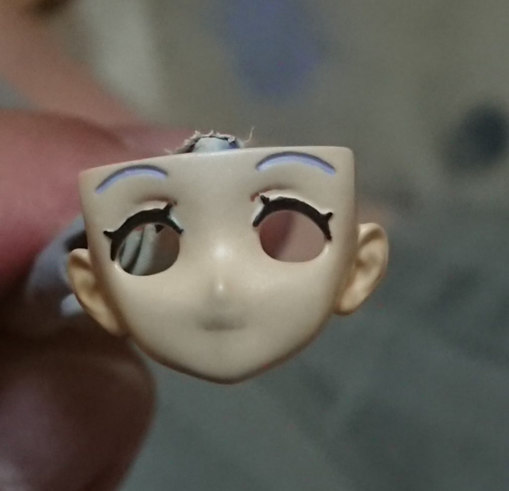 本当は加工途中の写真を撮っておけばよかったのですが、忘れてしまったので塗装後の写真をば。頬や唇を削ってアニメ的な凹凸の少ない形状に。顎を削って丸みをだし幼く見えるように・・・というモビルドールサラでは比較的定番の加工の他、もともとのモビルドールサラでは口角が上がっている唇の両端部を瞬間接着剤で埋めてならし、唇を真一文字に結んだ無表情顔に変更しています。元々の笑顔の造形が影響しているのか、光のあたりかたによっては影で口角が若干上がっているように見え、わずかにほほ笑んた表情に見えたりしてしまうのですが、これはこれで面白いかなと。眉毛はタミヤエナメルで髪の毛にザクっと近い色を作り、筆塗り後はみだしをふき取りしています。構造的に大半前髪に隠れるとこでもあるので、大まかに似せてれば目立ちませんね。