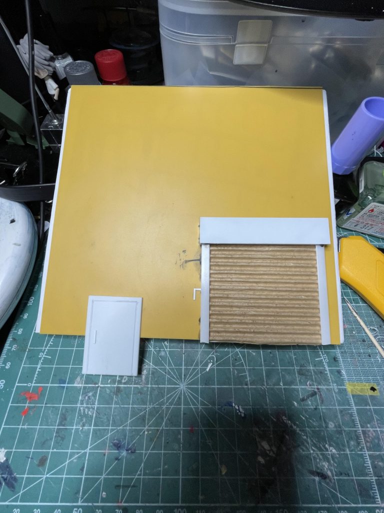 壁は、スチレンボードにプラ板をノリで貼ったものが素材です。扉やシャッター周りはプラ板やプラ棒。シャッターは段ボールの波波部分です。