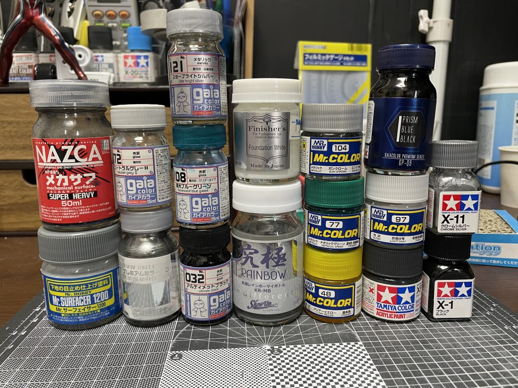 使用塗料は大体こんな感じ。白ベースにしたのは言われなくてもってとこですが特務隊意識してます。グレーの塗り分けは2日くらいかけてマスキングして分けましたがそれ用にディテール作ったのであまり苦じゃなかったです。差し色の黒っぽいのはガイアのプリズムブルーブラック。ミラークローム下地で塗装しました。新しい塗料は必ずテストしてから塗装します。一応下調べもしますがやっていいことと、いけないことは必ず体験してこの目で見ることにしてます。やらないと知識ばっかりの頭でっかちになっちゃいますからね。とにかくやり直しばかりで大変でした。投稿ページに当て込むと若干色変わりません？自分の画像フォルダと比較するとモノクロ感強くなってる気がするんですけど気のせいでしょうか？まぁ自分は全然オッケーです。以上です。ずるずる設定ご覧頂きありがとうございましたm(_ _)m次はGBSコンやります。