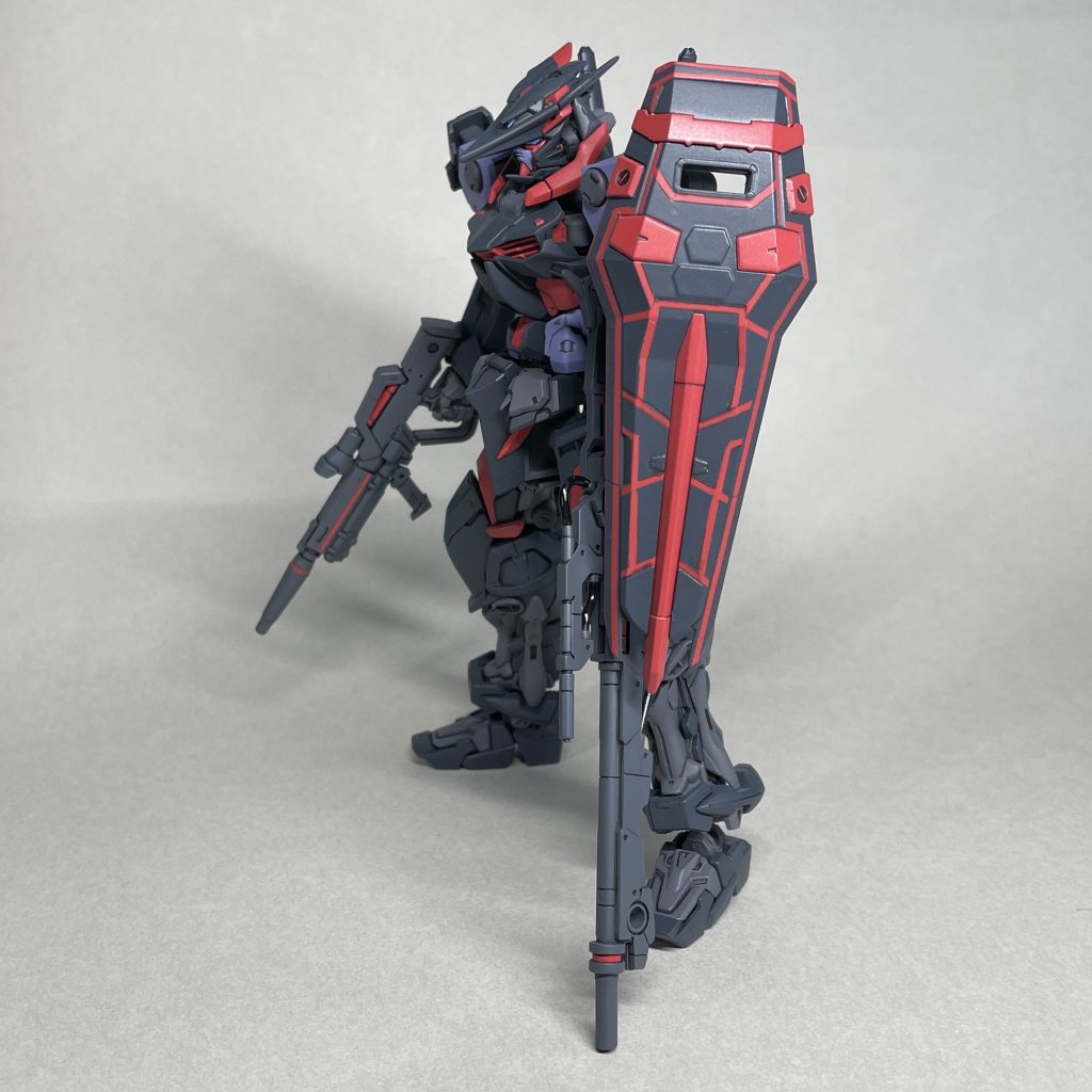 よこ 武装は、RGストライクガンダムのライフルとシールド、30MM のパーツを使ったライフルと右肩アーマー、 ガンダムイージスナイトの腕追加装甲を装着。 これまで何機かRGアストレイを作って飾っていますが、支えなしでは長期間の安定した自立は不安です。今回は、30MMの長いライフルで支えることで自立しやすくしています。一度、長いライフルを右手に持たせ左手にRGストライクのライフルを持たせてみましたが、左手の武器の支えがないとシールドが自重で下がったり左に傾いたりするので、左手に持たせないと具合が悪いようです。