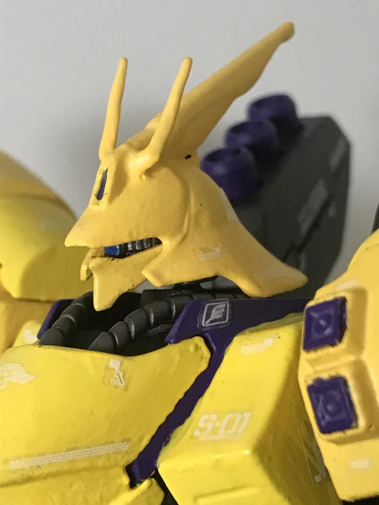 顔面ドアップ。モノアイのカメラの色は青。モノアイ稼働部はシルバー寄りのガンメタここまで寄ると筆塗りした下地塗料が綺麗に敷けてないのがわかります。パーツの縁やらにヨレヨレとした歪みが… ちゃんとしなさい機体カラーが黄色なので白の附属デカールも少し見づらい