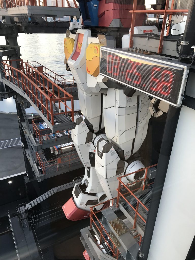 エレベーターに乗り込んで、5Fへ!このエレベーターのドアにガンダムの顔のイラストが描かれていて「抜かりない演出」にウキウキしていると到着。 下から見上げるのとはまた別格の迫力っ!(モールドはどうなっているのか、どんなデザインにリファインされているのか、コーションマークはどう配置されているのか)などなどを冷静に見る事が出来るまで少し時間がかかりました。 もう迫力にただただ圧倒されていたのでしばらく小声で「・・・スゲェ・・カッコイイ・・・ウワァ・・・」っと無心でガンダムをただただ眺めていると、起動実験までのカウントダウンがっ!そしていよいよ私の真横でガンダムが動き始めたのです。