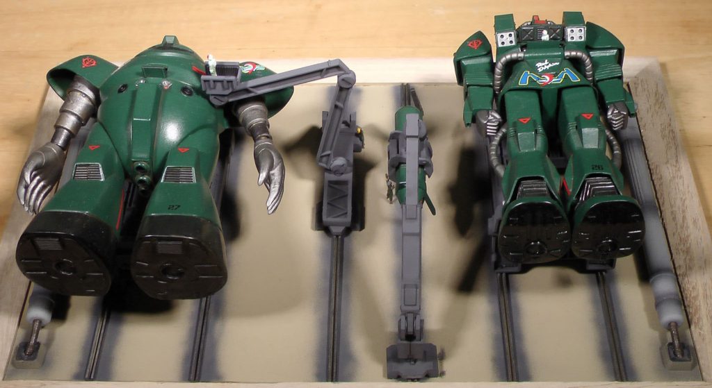 整備兵もたくさんいますが、武器クレーンの操作をしたり、核融合炉の燃料（重水？）のホースを収納したりしています。金髪の女性兵士は女性パイロットに手を振っています。