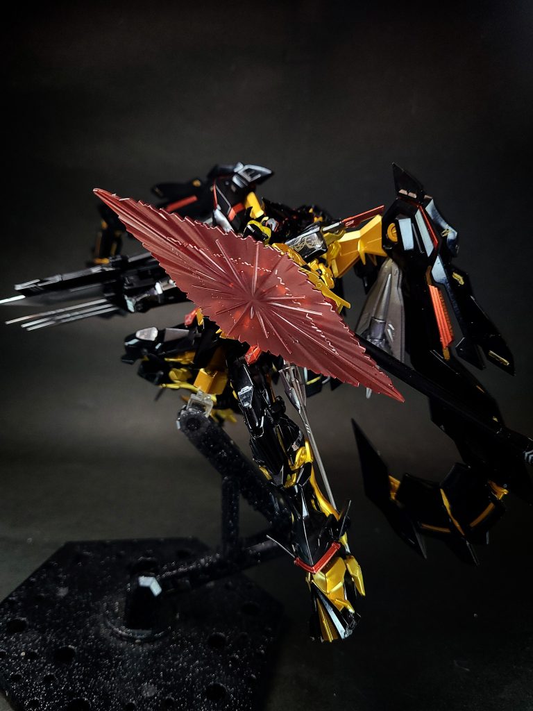 ツムハノタチ左前腕部に固定された鉤爪。この追加兵装はこれまでの実戦の結果において格闘戦となる状況が多く、右腕に固定されたトリケロス改の取り回しの悪さを補う為であろうと推測できる。敵機体に引っ掛けてバランスを崩したり自由を奪い、大きなダメージを与えることなく勝利するための武装。名称は八岐大蛇の尾の中から出てきたとされる剣・都牟刈大刀に由来する。これが後に天叢雲剣、あるいは草薙剣と呼ばれるようになる剣である。