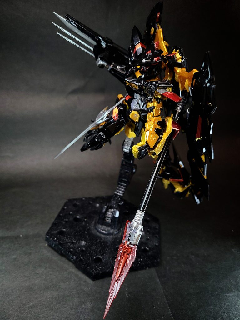 オキツノカガミビームシールドとビームソードの機能を併せ持つマルチウェポンで、槍のような外見をしている。ビーム発振装置の基部はワイヤーで射出することができ、ビームソード時には鞭の様にも使用できる[33][29]。左前腕部にツムハノタチと換装される形で装備される。「天空の宣言」後、賛同するものを無条件で守る為に短期間でかなりの戦闘を行い、それによる機体の損傷具合を見たユン・セファンによって開発されている。ビームシールドはロウ・ギュールによってもたらされた「アルミューレ・リュミエール」の技術を応用したものである[33][29]。名称は十種神宝のひとつ、沖津鏡に由来する。初出は月刊ホビージャパン2006年10月号[