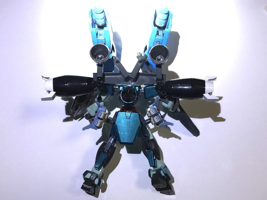 推進器兼サブアームユニット、腰部GNスラスター。腰部GNスラスターはスラスター機能と非常時の粒子撹乱ミサイル(左右2発ずつ)の格納スペースを両立させようとした結果、某組織のスペースシップと似た形状になってしまった。サブアームに懸架された装備含め機体の総重量は凄まじいのだがGN粒子の副次的効果(質量軽減)により鈍重な外見に反して無重力・重力圏問わず軽快に動き回る事が可能。