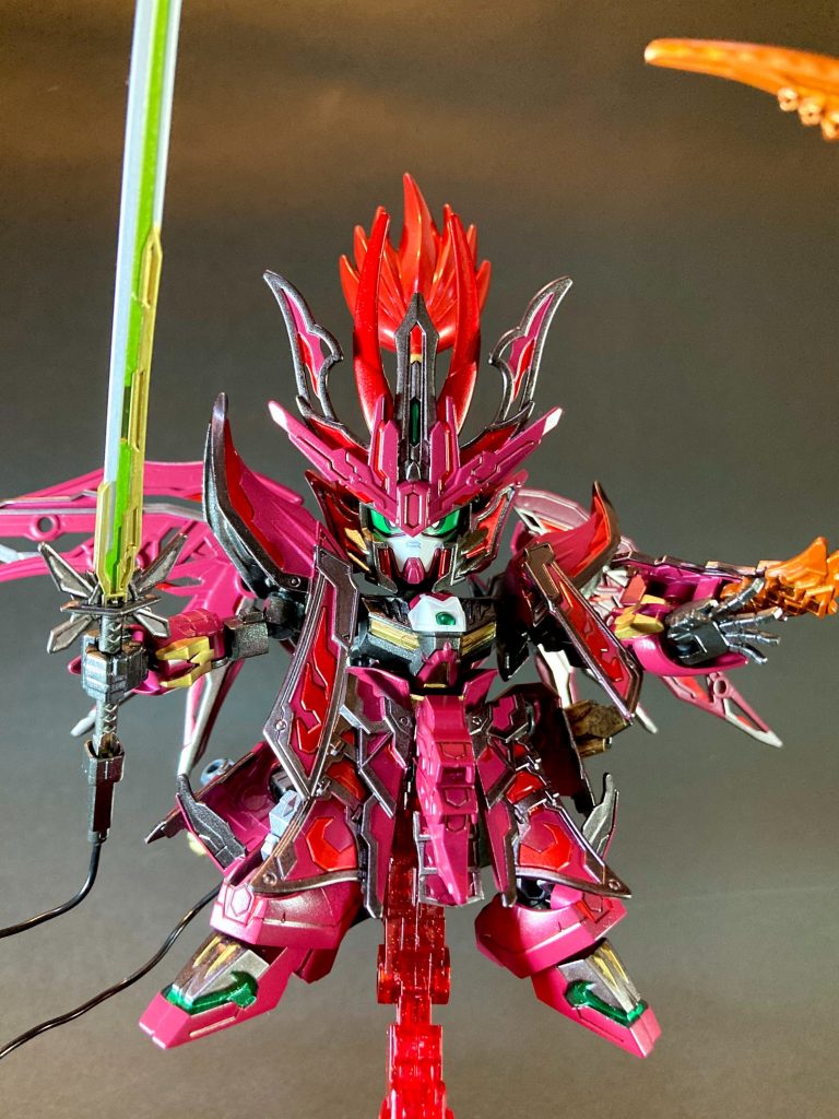 他、緑色のビームソードに合わせて大太刀の差し色をライトグリーンに、大出力バルジ斬りをイメージして剣撃のエフェクトも同様にライトグリーンにしました。剣から腰部ジェネレーターに有線接続するコード、ヒートロッドの赤熱化表現でオレンジ色のパーツを用意するなど、出来るだけ元MSのガンダムエピオンの特徴を盛り込んでいます。ラフ造型時は倚聖パーツの主張が強くてゴテゴテな感じがありましたが、全体をエピオンカラーで統一したところ結構馴染んでくれてまとまったデザインになってくれたかなと思います。また設定上は、曹操の倚聖の装と似た形状の鎧甲冑が顕現するのは、依代である倚聖剣と第六天魔王剣が同一刀匠の鍛えし兄弟刀であるため、というイメージで設定させて頂いております。