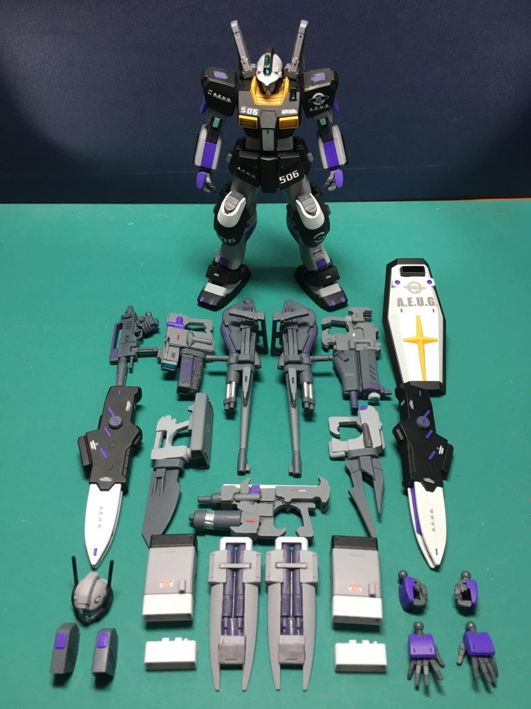 作成した全オプションとともに。元のジムⅢ自体割と合わせ目が多いので、オリジナル装備各種も含め結構ヤスリ掛けが大変でした。お正月休みは長くとれたのでそこでヤスリ掛けから大まかな塗装までできたのは幸いでした。 塗装は今回缶スプレーを中心にしています。成型色のオレンジが強くてライトグレーのサフでは下地が透けてしまい、なかなか発色せず大変でした。黒=Mr.フィニッシングサーフェイサー1500(ブラック)本体グレー=Mr.フィニッシングサーフェイサー1500、途中で切れてストックが無くなりのでMr.サーフェイサー1000も併用白=Mr.ベースホワイト1000紫=ガンダムマーカー ガンダムパープル武器等グレー=同グレー武器等グレー2=同メカグレー青=同メタブルー トップコート後はホイルシールをセンサー部に貼り、いつも通り肘と膝関節にはホイルシールの縁の銀のシールを貼っています。 ヤスリ掛けの物量が多くて辟易しましたが、鉄ヤスリや240番手の紙やすりに助けられてどうにかこうにか完成までこぎつけました。