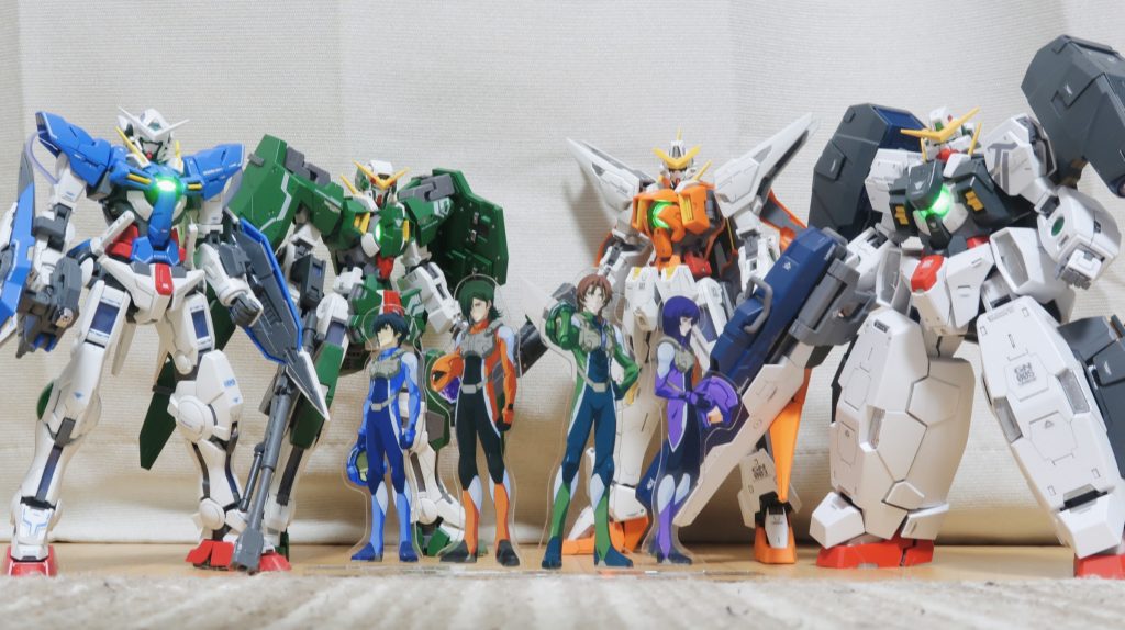 ガンダムカフェで購入したアクリルスタンドと一緒にMGのソレスタルビーイングの機体を撮影しました。宣伝ポスターぽくてめっちゃ合います！ 