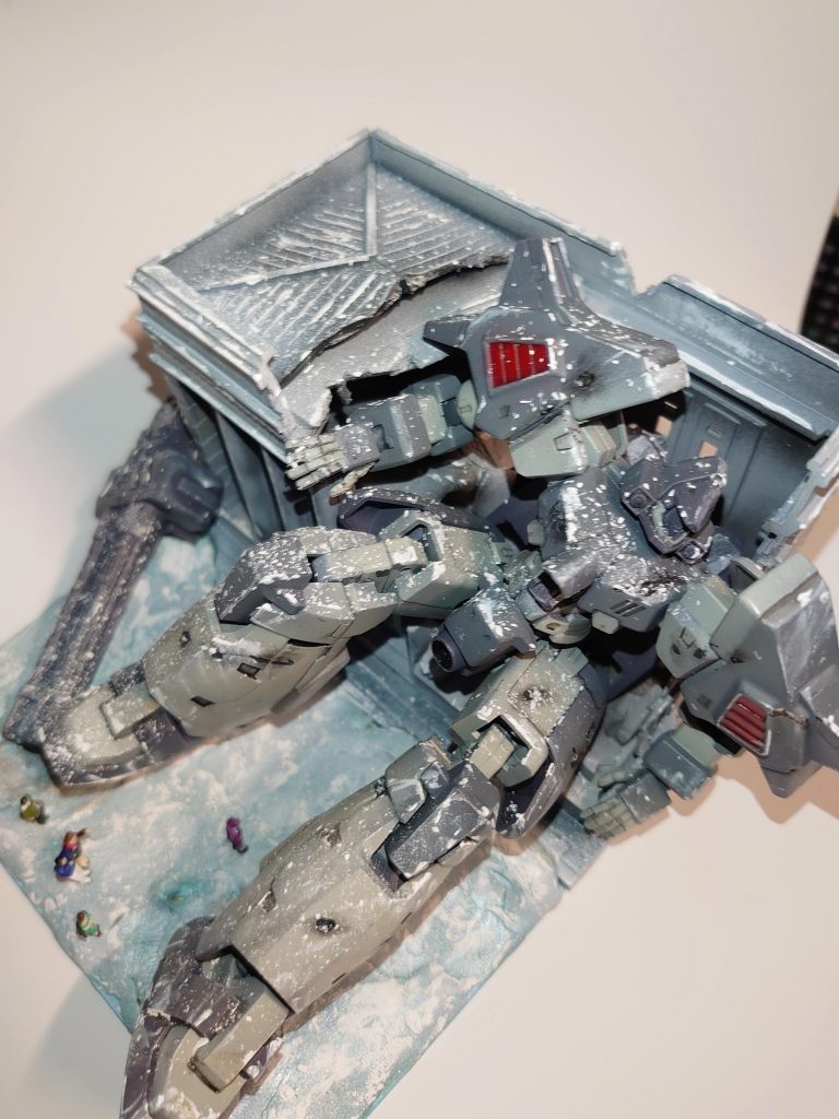 崩れた建物の壁に手をかけているのは、再び立ち上がろうとして断念したのか?コクピットハッチは開け放たれ、パイロットが下に降りている。