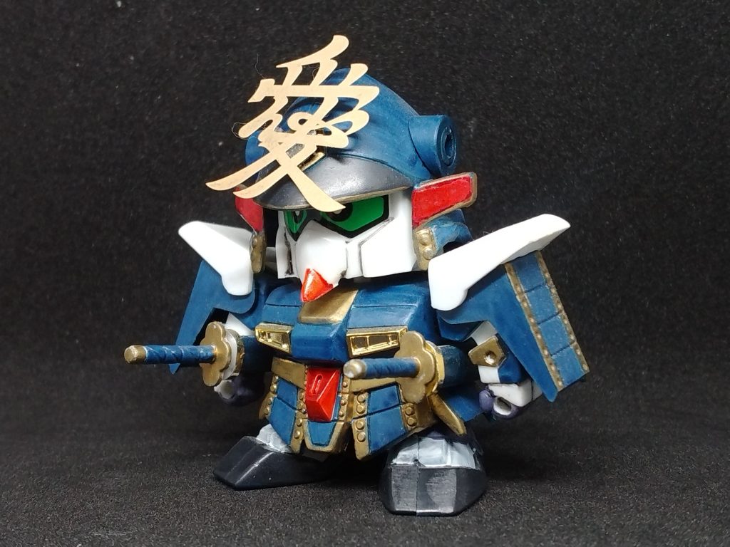 SD戦国伝 天と地と版 兼続頑駄無。武神降臨編にあって天と地とには無い武者です。武神降臨編の直江兼続頑駄無が天と地とにもあったら、と摩亜屈を…て見れば解りますねι武神降臨編の直江兼続頑駄無を参考に少しゴールドのアクセントを増し。このキットを組んだ方ならご存知だと思いますが、メタリックと云うか変なラメ入りのプラスチック成形であるため、こちらはパチ組みガンダムマーカー(エゥーゴセットのMk=IIカラー)ながら全塗装しています。前立の愛の字は当時流行った携帯電話デコシール(金属製エッチングシール)です。武者仁宇買って幸村頑駄無も続けたいと思いながら、未だに入手できずに四人目作れず時間ばかり経ってしまっていますι(何度か行ったガンダムベースでも見つけられていない)…実は違う武神降臨編モチーフの武者に手を付け始めているのですが、それはまたの機会に。