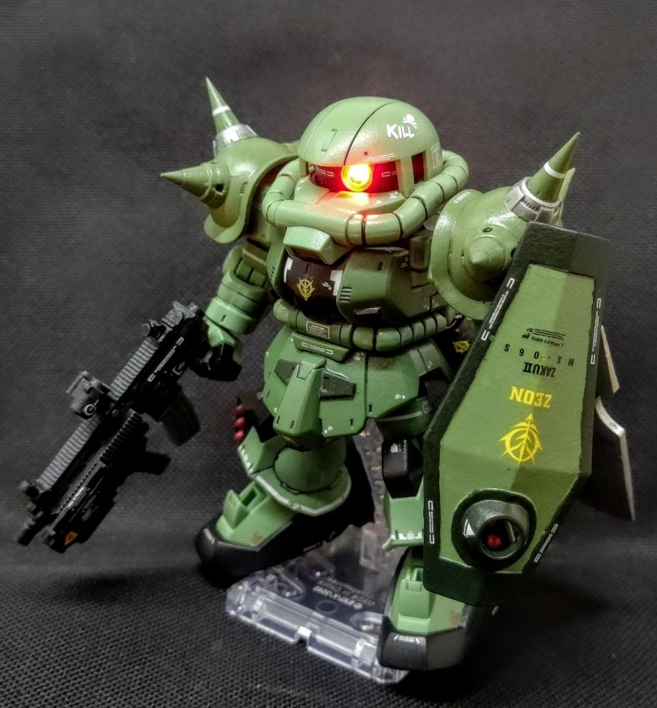 脳内設定MS-06　ZAKUⅡF  宇宙世紀７８年3月18日第３次降下作戦でアフリカに降下、現地で改修を受けたバリエーションの一つ。東アフリカ戦線では大地溝帯に伴う落差１００メートルの断崖が随所に存在する地形に適応すべく軽量化と各所アポジモーターの増設、背部に大型スラスターを装備した機体。当初は重装備をし単騎、無いし小隊規模で強襲戦闘を想定していたが燃料の増設に難を発した問題で企画倒れとなった。大出力で肉薄し大型戦斧を以ってを与える一撃離脱の奇襲戦闘を得意とする。グレネードを装備した120mmマシンガン、脚部３連ミサイルランチャーを武装し、シールド裏などにハンドグレネード等を装備出可能（３ミリ穴２つ有りｗ）。