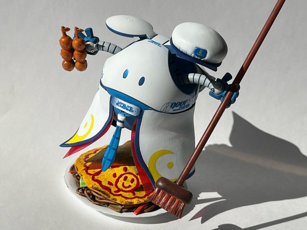 衣装は「未来の僕らは知ってるよ」をイメージ。右手には千歌ちゃんと食べたかったみかんアイス、左手にはデッキブラシを持たせました。どちらもあの神回「友情ヨーソーロー」で登場した印象深いアイテムです。