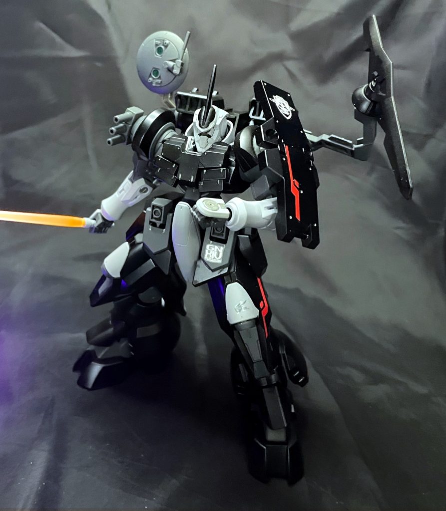 以下、設定GN-X-Ⅳ過渡期に評価用として開発された機体を陸上における狙撃戦を想定しカスタムしたもの。場所がばれても居座って狙撃が継続できるように重装甲化されている。ホバー移動を採用したことにより移動中も安定した照準が可能となっている。