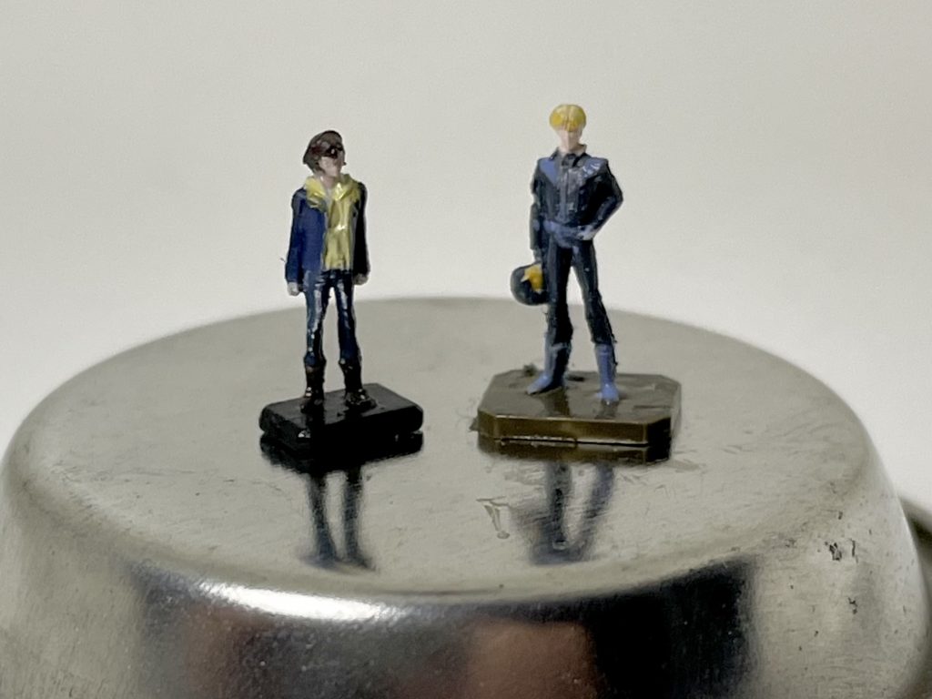 1/144 パイロットフィギュアも塗装しました。バナージ・リンクスとリディ・マーセナス(余剰パーツ)です。アクリジョン のつや消しクリアを拭いてから水性ホビーカラーで筆塗りしてます。塗料皿に両面テープで貼り付けて塗るとやりやすいです。このサイズだと色で似せるしかないんだけど、いまいち似てないね。
