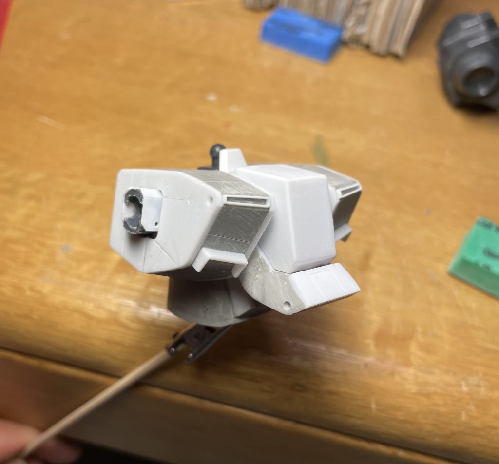 以下改修ポイント　頭部：写真ありませんがモノアイスリットが幅長さともに大きすぎるのでパテプラ板で修正。クチバシをプラ板で作り直して中にoボルトを仕込みました。パイプの出る両頬のダクトの形状変更のためカバーをプラ板で制作。胴体：胸部を3分割し、中央ブロックをプラ板箱組みでスクラッチ。両側面ブロックはそれぞれの端面に外形を理想の形に大型化するよう1ミリプラ板を貼り付け、間をパテ埋め。中央赤色ブロックを大型化。腹部はプラ板パテでスクラッチし大型化。肩関節はボールデンアームアームズのボールジョイントをしこみました。