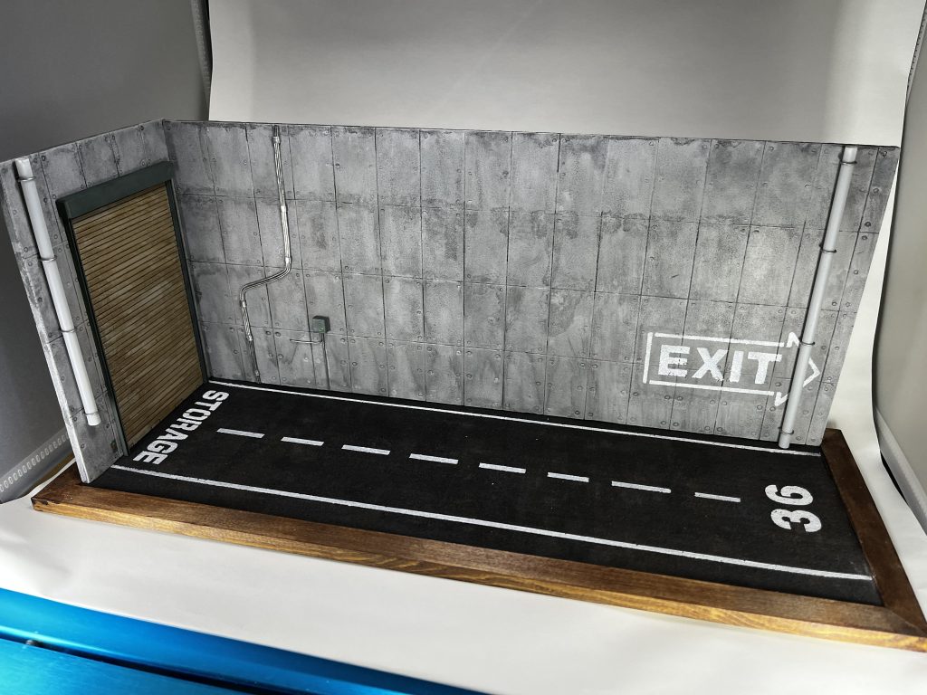 ジオラマのみで。左側のシャッターから奥はなんらかの格納庫となっており、ここは格納庫の外というイメージで作っています。コンクリートの壁、路面のアスファルトをメインに排水管や電線的なものをプラパイプやはんだ線で表現しました。