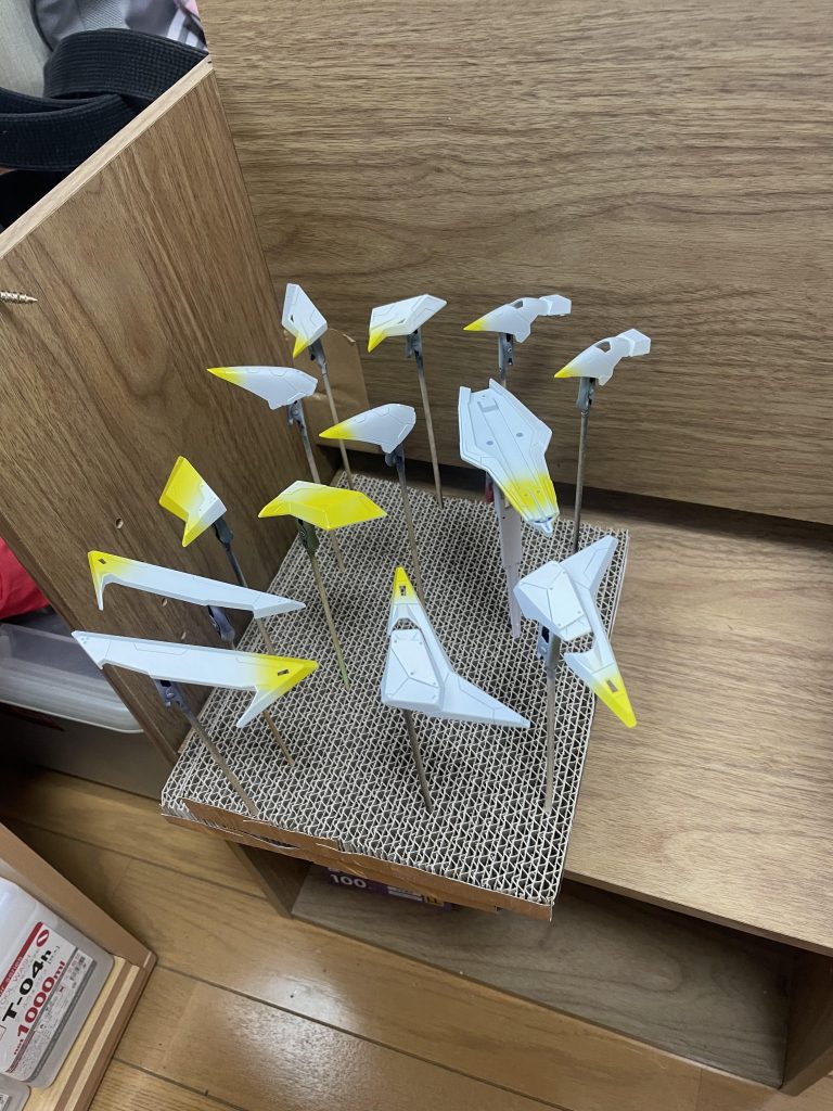 塗装は塗り分けのためにかなり順序を考えながら行いました。塗装は全てガイアノーツの塗料です。基本的には白サフ、黒サフを使い分け、フレームはガンメタサフで仕上げ。その後サンシャインイエロー+蛍光イエロー1:1で塗装。メインカラーはニュートラルグレーⅤ、部分的にⅣ、また一部スターブライトゴールド、シルバーを使っています。またバーニア内部はシルバー上から蛍光オレンジを塗っています。仕上げ後のレッドポイントのみアクリジョンの蛍光レッドを筆塗りしました。これに関しては塗装してから貼り付ければよかった…反省です。またモールドへのスミ入れはシルバーで行っています。