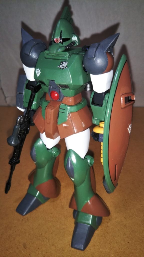 正面素立ちです。 メインで使用したキットは、旧HGUCのギャンです。 各部の改修はストーリー投稿をご覧になっていただいた方が分かると思いますので、今回は主に塗装について説明したいと思います。 基本塗装は緑にニュートラルグレーを混ぜた少し明るめのグリーンと、レッドブラウンにミドルストーンをまぜた茶色、ニュートラルグレーにツヤ消し黒を混ぜた暗めのグレーの3色です。 上腕部と太ももはツヤ消し白です。 関節やバーニア類には黒鉄色やミッドナイトブルーなどを塗装してあります。 マーキングは注意書きやジオンマークのほかに、胸部にジオン公国防衛部隊のマークを入れてみました。 こちらのマーキング、本機「ガルバルディα」が活躍する「ギレン暗殺計画」というマンガに登場する、ペズン計画のテストパイロット、フィーリウス・ストリーム中尉の機体と同じモノをイメージして入れました。しかしながら、マンガ本編に登場するフィーリウス機のガルバルディαは隊長機であることを示すアンテナが付いている上カラーリングも若干異なります。 それでも、個人的にイラストなどで一般的なこのカラーリングの方が好みであることと、この機体にアンテナはちょっと似合わない気がしたので、オリジナルのイラスト仕様としました。 ですが、ジオン公国防衛部隊のマーキングはどうしても入れたい・・・。 そこで本機は「フィーリウスの駆るガルバルディαの予備機」という設定で製作しました。 「オレ設定」というヤツは、こういうときに非常に便利です(笑)。